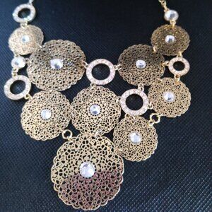 A preowned gold necklace designed in a mix of lacy look circles and rhinestones.